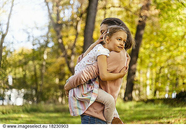 Mother carrying daughter in park