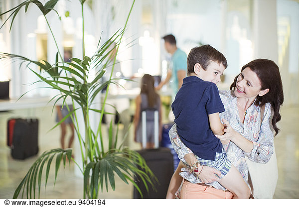 Mother carrying son in hotel lobby