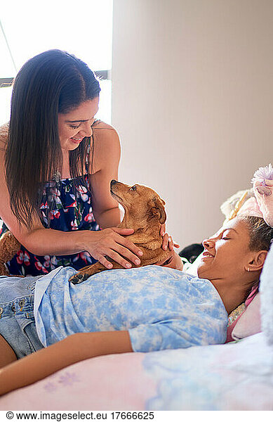 Mother  disabled daughter and cute dog cuddling on bed at home