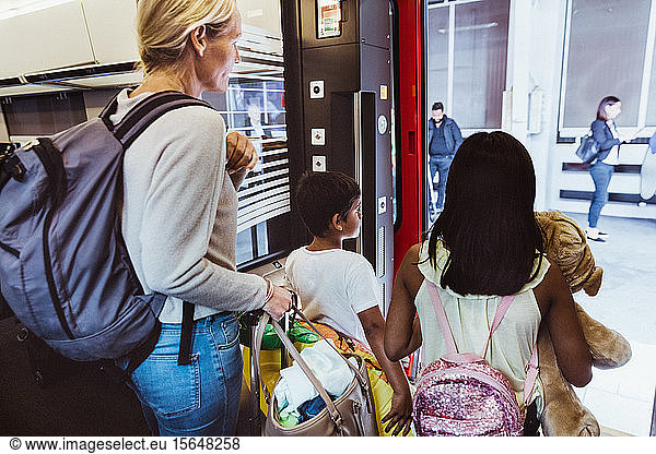 Mother disembarking train with children in city