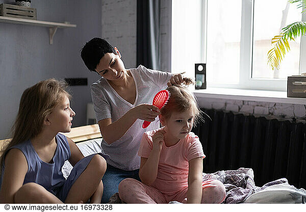 Mother doing hair of daughters in morning