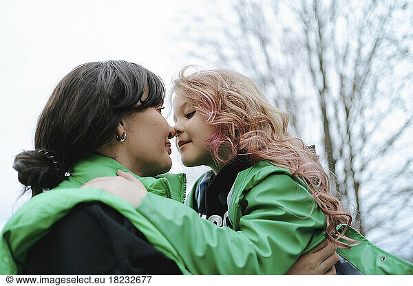 Mother embracing daughter with pink hair at park