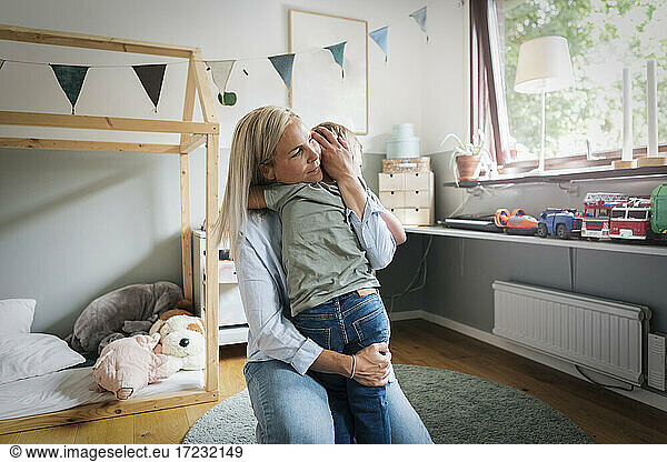 Mother embracing son in bedroom at home