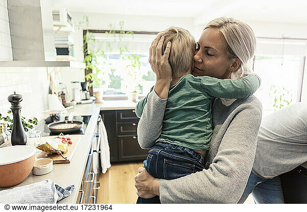 Mother embracing son in kitchen at home