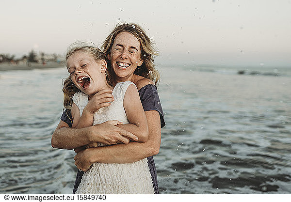 Mother embracing young girl with freckles in ocean