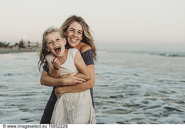 Mother embracing young girl with freckles in ocean