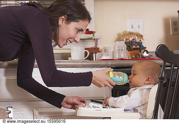 Mother feeding her son drinking from sippy cup
