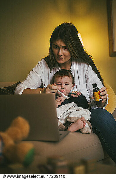Mother feeding medicine to daughter in living room