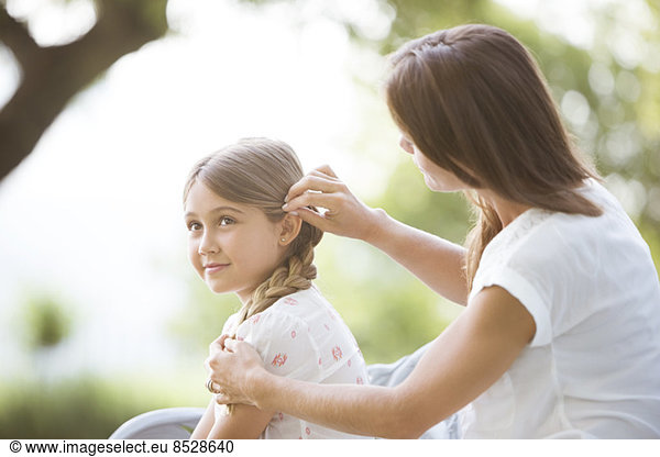Mother fixing daughter's hair outdoors