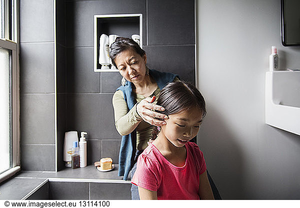 Mother grooming daughter in bathroom