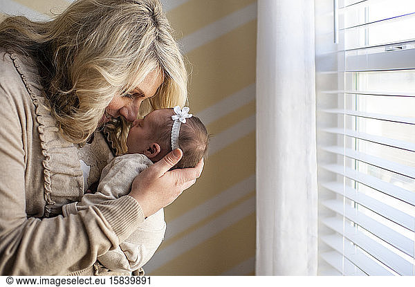 Mother happily holding newborn daughter up to face at home