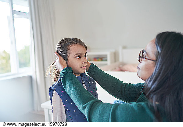 Mother helping daughter fix hair
