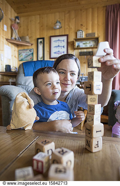 Mother helps son build block tower.