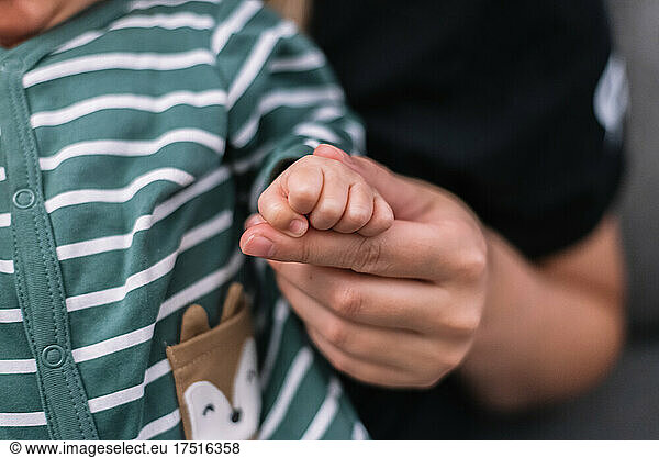 Mother holding her newborn baby's hand