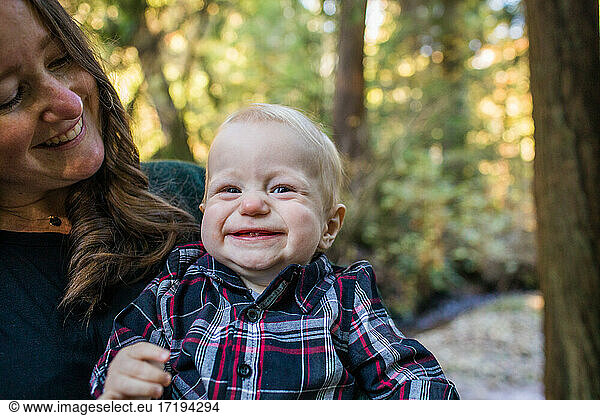 Mother holding her one year old son  laughing in nature.