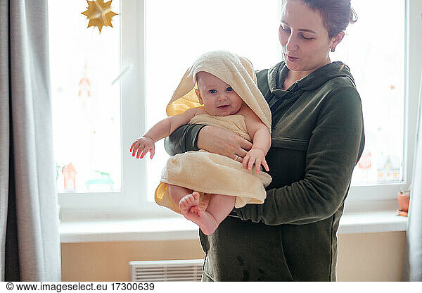 Mother holding little baby wrapped in towel