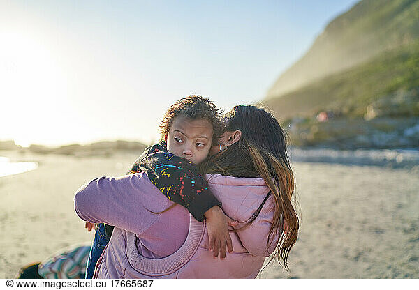 Mother holding son with Down Syndrome on sunny beach