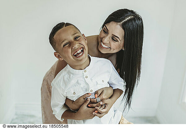 Mother hugging son from behind and looking at him in studio