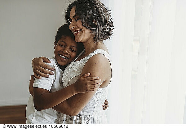 Mother hugs school-aged son in smiling embrace