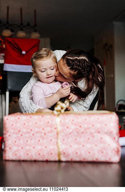 Mother kissing daughter during Christmas celebrations