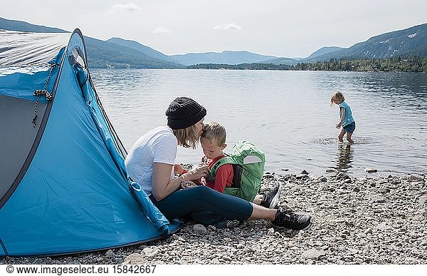 mother kissing her son whilst camping in a tent with family by sea