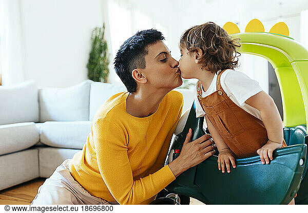 Mother kissing son in living room at home