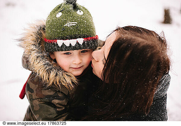 Mother kissing son outdoors in winter