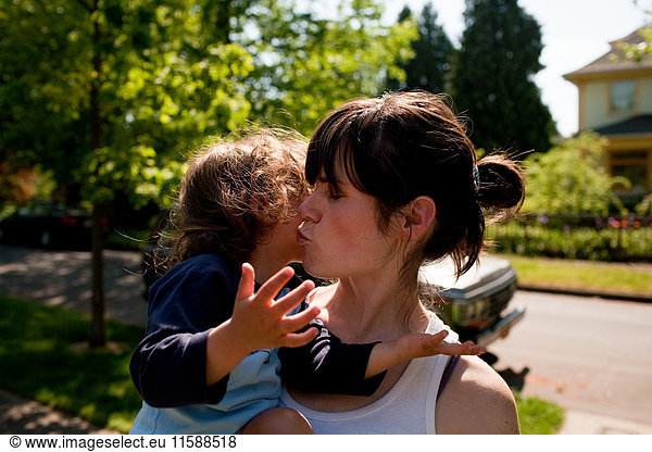 Mother kissing toddler daughter