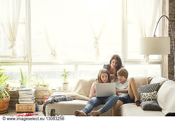 Mother looking at children using laptop computer