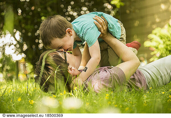 Mother lying in the garden and playing with her son