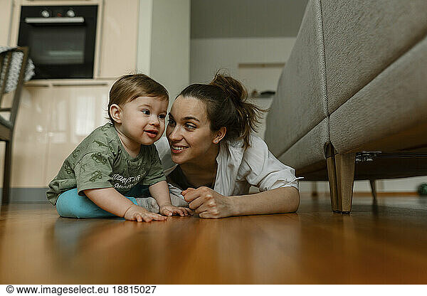 Mother playing with baby girl on hardwood floor at home