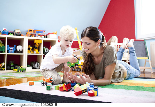 Mother playing with her little son on the carpet of children's room