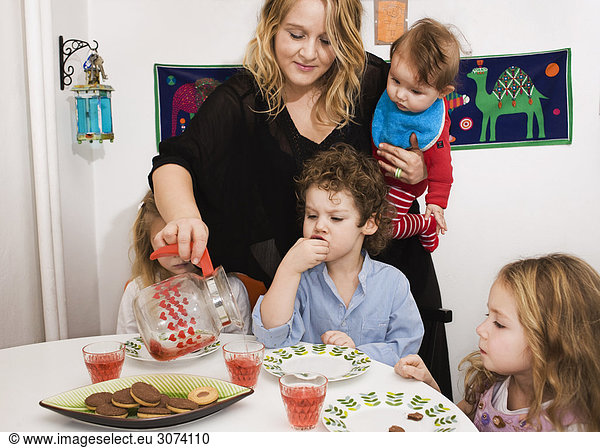 Mother pouring out a fruit drink to her children Sweden.