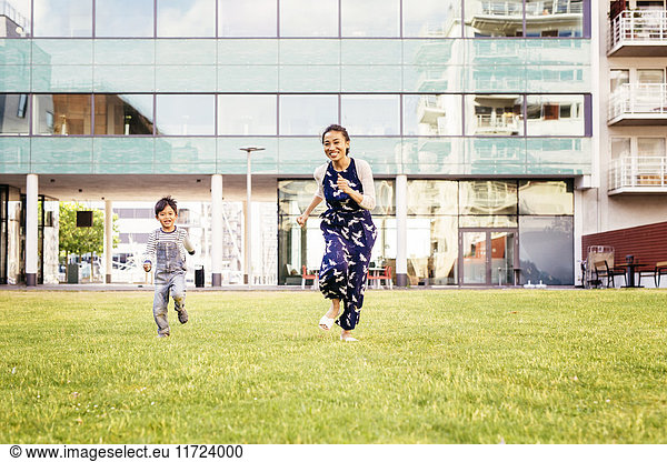 Mother running with son (4-5) on grass