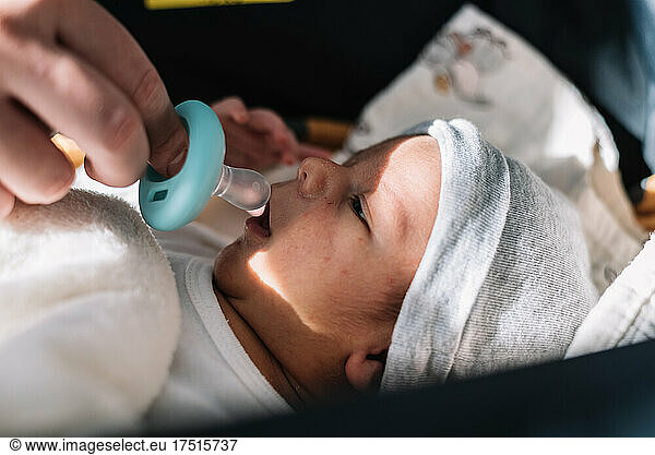 Mother's hand putting pacifier to her newborn baby.