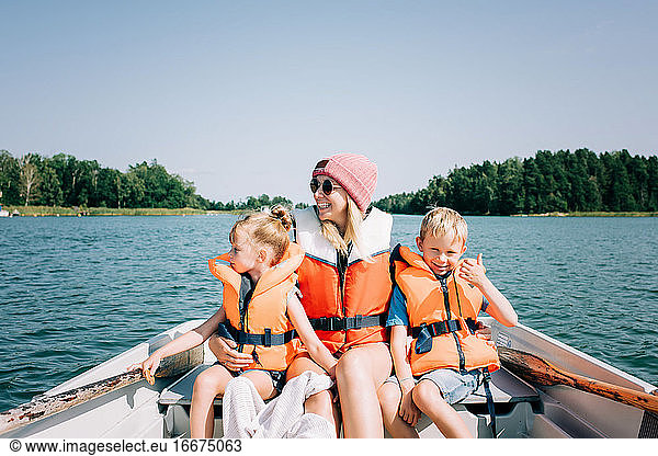 mother sat happily with her kids on a boat enjoying summer in Sweden