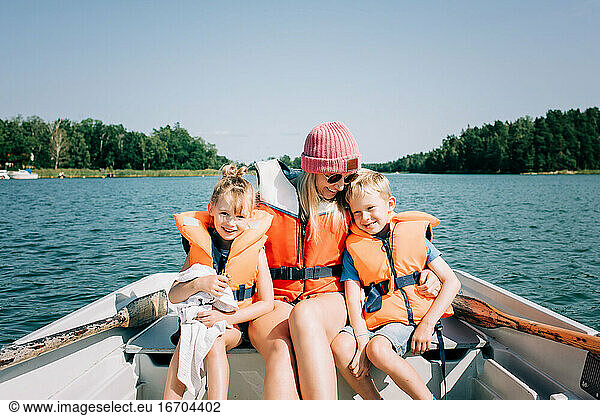 mother sat on a boat hugging her kids happily in summer in Sweden