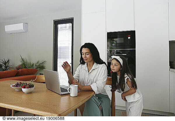 Mother sharing laptop with daughter at home