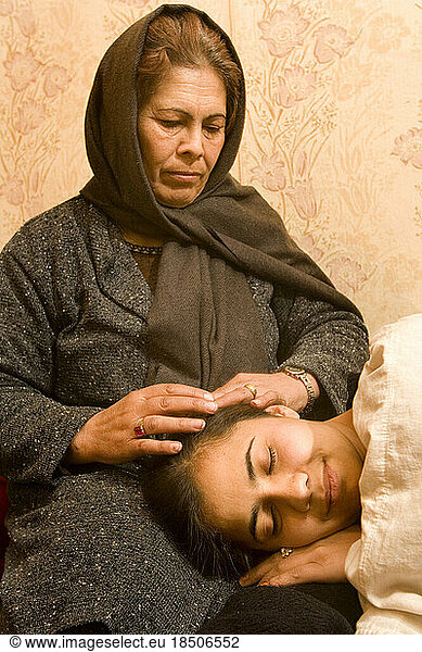 Mother strokes her sick daughter's hair in Kabul.