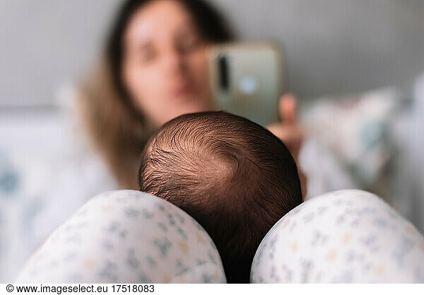 Mother taking a photo of her baby with her cell phone.