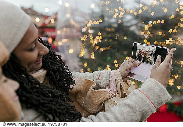 Mother taking selfie with son through smart phone at Christmas market