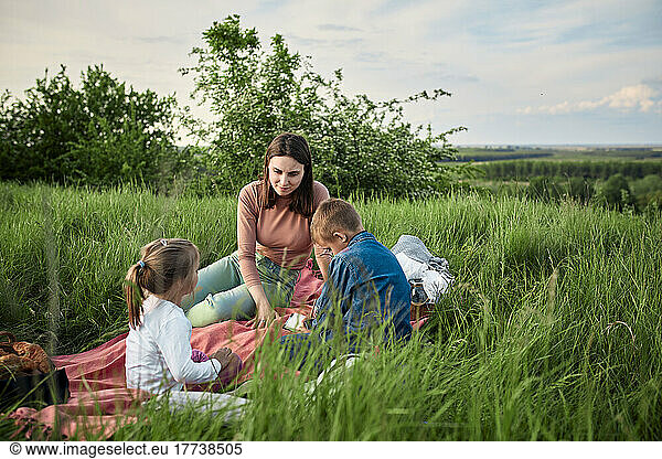 Mother talking to children on picnic in field