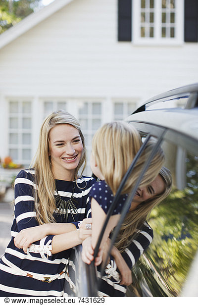 Mother talking to daughter in car window