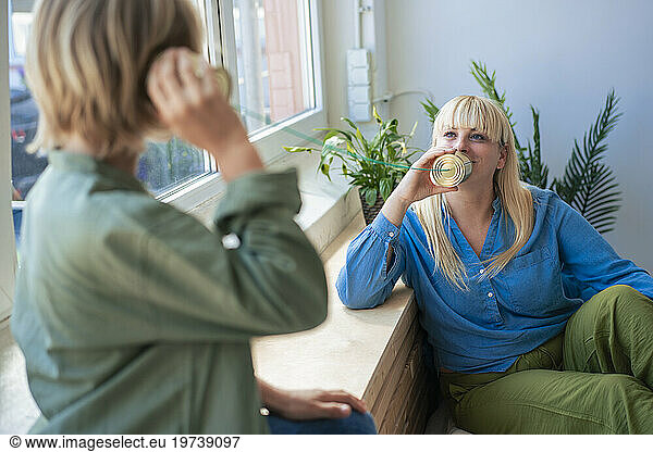 Mother talking with son through tin can phone