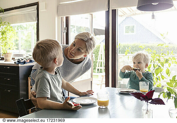Mother talking with son while having breakfast on dining table at home