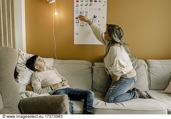 Mother teaching autistic son in living room