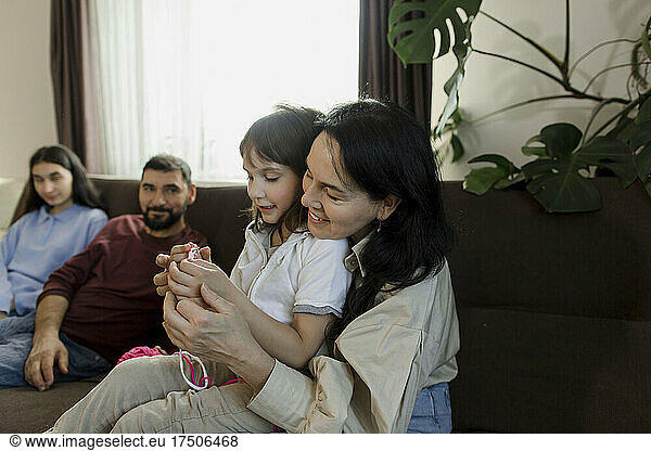 Mother teaching daughter crocheting wool at home