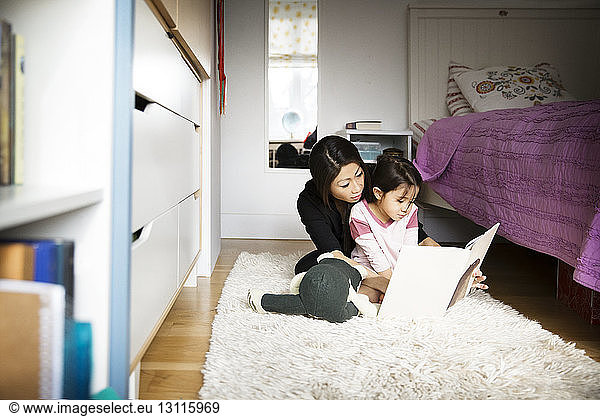 Mother teaching daughter while sitting on carpet in bedroom
