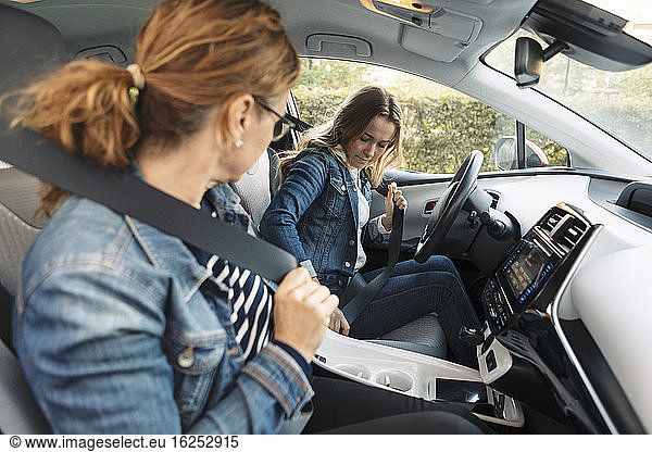 Mother teaching teenage girl driving during weekend