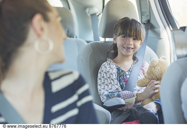 Mother turning and smiling at daughter in back seat of car